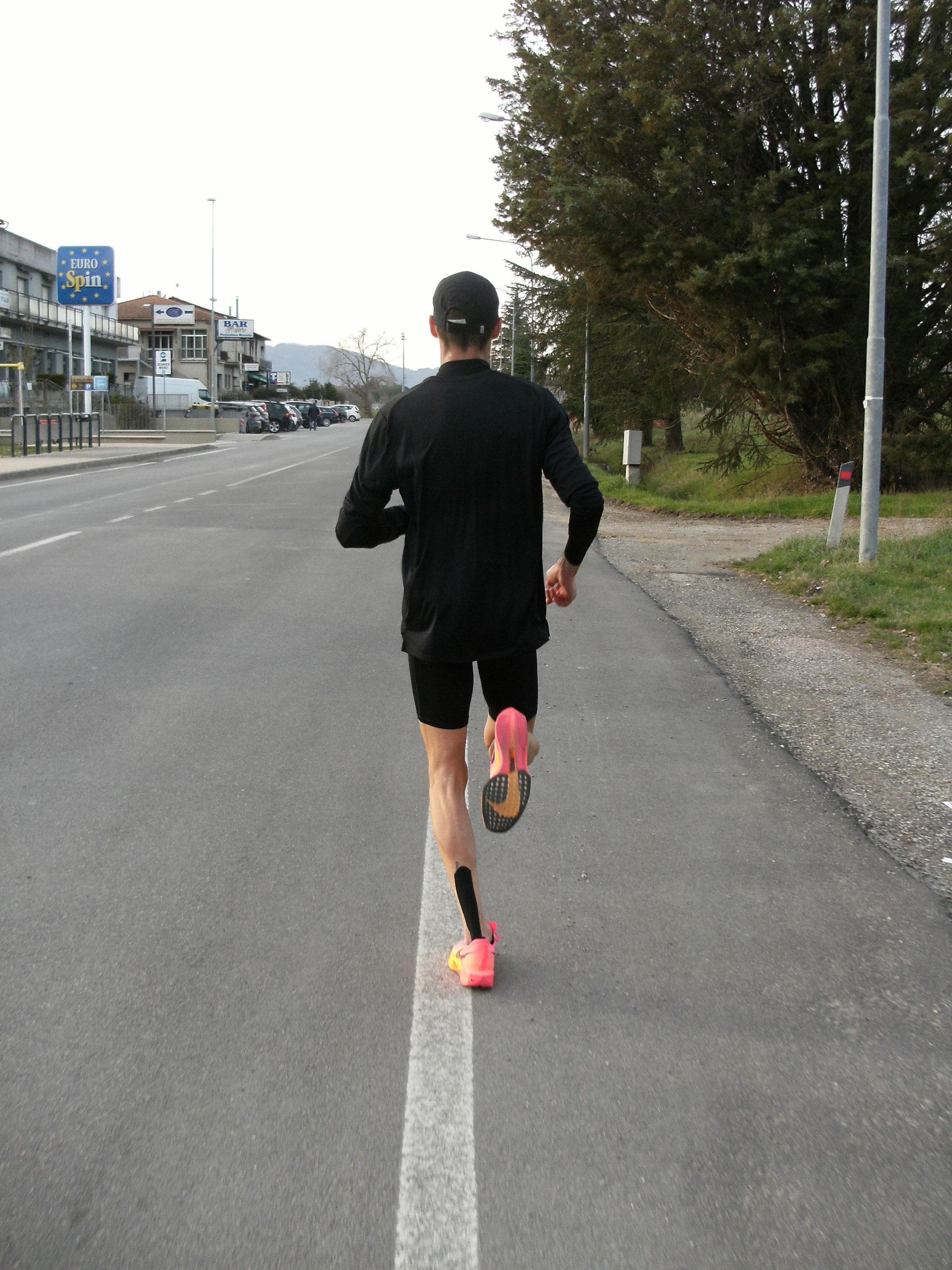 Leonardo Grilli corre lungo la linea bianca di una strada, ripreso da dietro.